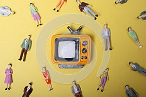 Figurine people around retro syled tiny television