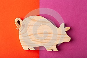 A figurine of a pig carved out of solid pine by a hand jigsaw. On a multi-colored background