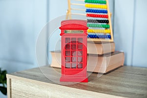Figurine of a red telephone booth on shelf. Mini figurine of London Telephone Booth for sale as souvenir. Telephone booth present.