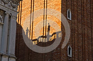 Figurine shadows on a Campanila bell tower wall at piazza San Marco in Venice