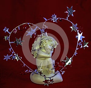 Figurine of a sleeping angel on a red background.