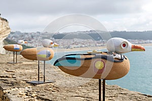 Figurines of seagulls with the image of Jacques-Yves Cousteau on the wall of the fortress in Nazare close up