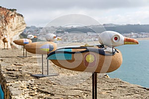 Figurines of seagulls with the image of Jacques-Yves Cousteau on the wall of the fortress in Nazare close up