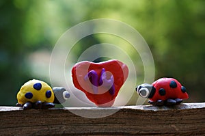 Figurines of two ladybirds made of plasticine. There`s a heart between them. The number 14 is on the heart