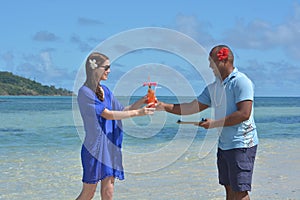 Fijian man serve a tropical cocktail drink to a tourist woman in