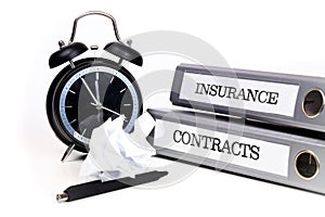 File folders and alarm clock symbolize time pressure while working on contracts and insurance