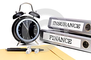 File folders and alarm clock symbolize time pressure while working on finance and insurance