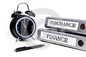 File folders and alarm clock symbolize time pressure while working on finance and insurance