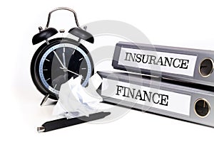 File folders and alarm clock symbolize time pressure while working on finance and insurance