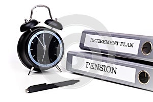 File folders and alarm clock symbolize time pressure while working on retirement plan and pension