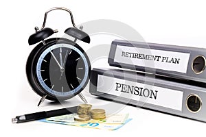 File folders and alarm clock symbolize time pressure while working on retirement plan and pension