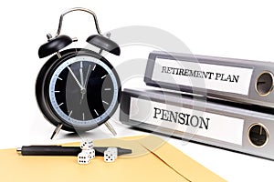 File folders and alarm clock symbolize time pressure while working on retirement plan and pension