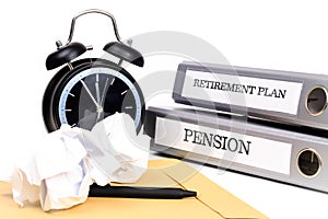 File folders and alarm clock symbolize time pressure while working on retirement plan and pension