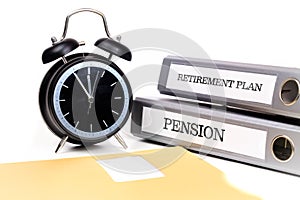 File folders and alarm clock symbolize time pressure while working on retirement plan and pension