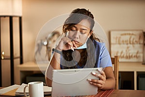 Filipina nurse working from home doing paperwork and using tablet