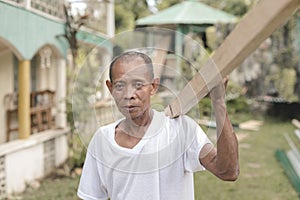 A filipino carpenter carrying a 2x2 peice of lumber on his shoulder. At a home renovation site photo