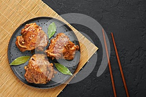 Filipino Chicken Adobo on dark gray plate on black slate backdrop. Filipino food. Braised chicken thighs