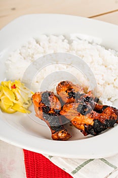 Filipino chicken barbecue with rice and pickled spicy green mangoes