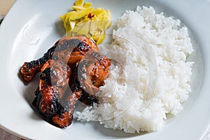 Filipino chicken barbecue with rice and pickled spicy green mangoes