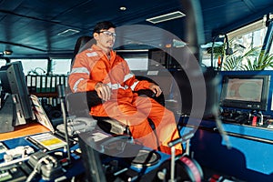 Filipino deck Officer on bridge of vessel or ship. He is looking forward to sea