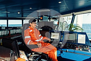 Filipino deck Officer on bridge of vessel or ship. He is looking forward to sea