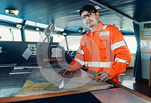 Filipino deck Officer on bridge of vessel or ship. He is plotting position on chart