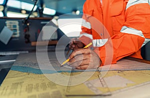 Filipino deck Officer on bridge of vessel or ship. He is plotting position on chart