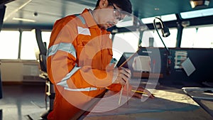 Filipino deck Officer on bridge of vessel or ship. He is plotting position on chart