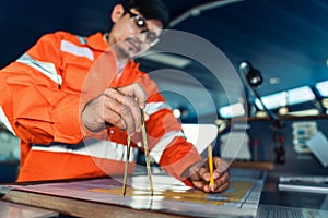 Filipino deck Officer on bridge of vessel or ship. He is plotting position on chart