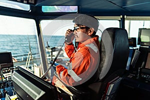 Filipino deck Officer on bridge of vessel or ship. He is speaking on GMDSS VHF radio