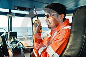 Filipino deck Officer on bridge of vessel or ship. He is speaking on GMDSS VHF radio