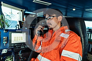 Filipino deck Officer on bridge of vessel or ship. He is speaking on GMDSS VHF radio