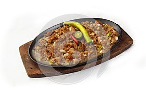 Filipino dish called Sisig or chopped pig face served with egg and chilli on a sizzling plate