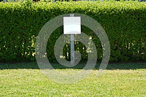 `fill in the blank` sign with hedge and green grass