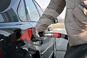 Fill the car with fuel. woman at a gas station with a bandaged finger tucks the car