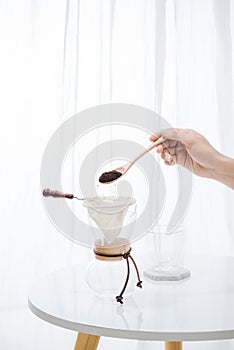 Fill grind coffee in filter with wooden spoon