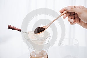 Fill grind coffee in filter with wooden spoon