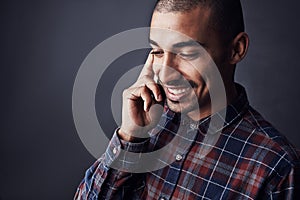 Fill me in on the details. Studio shot of a young man talking on a cellphone against a dark background.