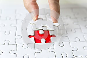 Fill the missing parts of hand white jigsaw concept puzzle for succeed