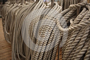 Filled frame background wallpaper photo of rows of beige plaited nautical tow ropes reeled together, hanging in lines on the deck