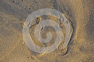 Filled frame close up background wallpaper shot of human foot prints on a yellow sand beach surface forming beautiful patterns and