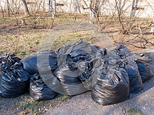 Filled with garbage black plastic bags on the street, garbage collection concept, street cleaning