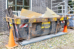Filled waste container in an old street on a home renovation construction site