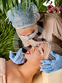 Dermal fillers of woman in spa salon with beautician.