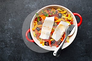 Fillet of cod. Fish dish. Oven baked white fish on a vegetable pillow. Tomatoes, capsicum, lemon, olives and fish. Top