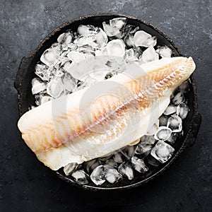 Fillet of cod fish. Saltwater white fish, raw before cooking. Healthy food ingredients. On a dark background