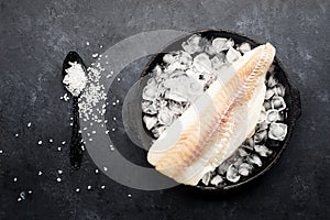 Fillet of cod fish. Saltwater white fish, raw before cooking. Healthy food ingredients. On a dark background