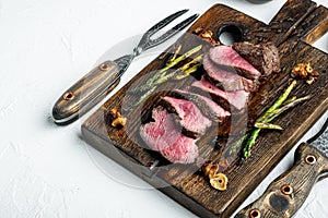 Fillet Mignon tenderloin Grilled and sliced meat beef steaks medium rare, with onion and asparagus, on wooden serving board, with