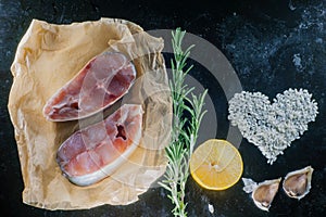 Fillet of raw fish and ingredients for cooking on a dark background