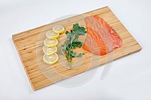 Fillet smoked trout with fresh herbs and lemon on a board. Seafood, isolated